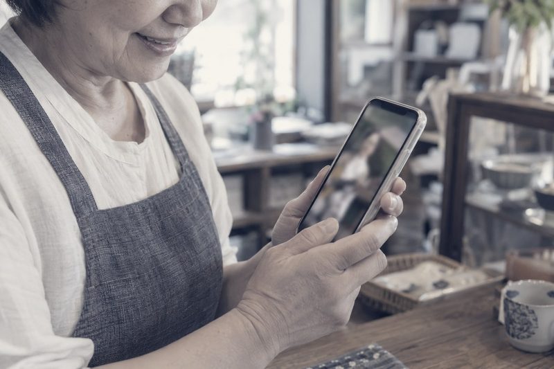 完成した動画をスマートフォンで確認する店主